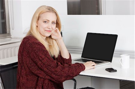 simsearch:693-06435941,k - Portrait of happy young businesswoman with laptop sitting at desk in office Stock Photo - Premium Royalty-Free, Code: 693-06435791