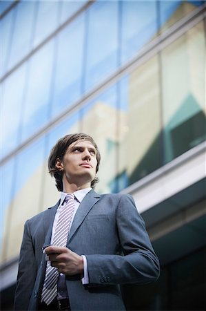 Low angle view of young businessman in suit looking away Stock Photo - Premium Royalty-Free, Code: 693-06435816