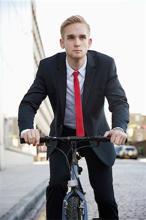 simsearch:693-06403504,k - Young businessman riding bicycle on street Stock Photo - Premium Royalty-Free, Code: 693-06435826