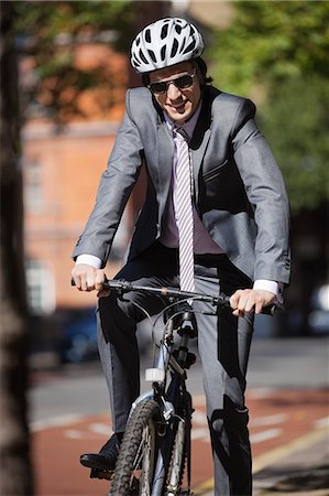 Portrait of happy young businessman riding bicycle Stock Photo - Premium Royalty-Free, Code: 693-06435820