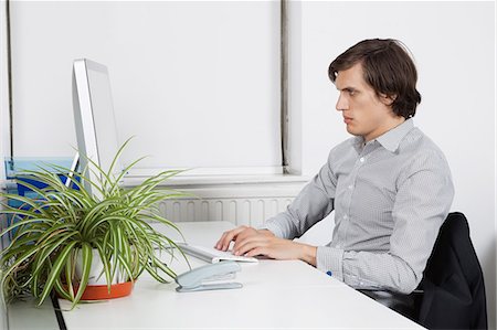 Young businessman typing at office desk Foto de stock - Royalty Free Premium, Número: 693-06435836