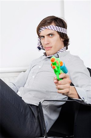 pistola de agua - Portrait of young businessman holding toy gun Foto de stock - Sin royalties Premium, Código: 693-06435842