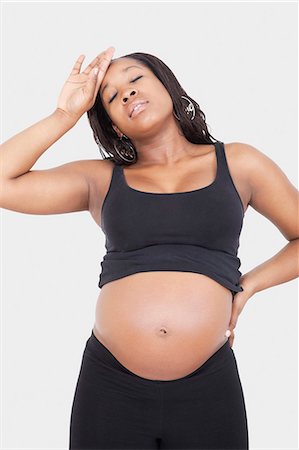 pregnant woman standing white background - Tired young pregnant woman over white background Stock Photo - Premium Royalty-Free, Code: 693-06435856