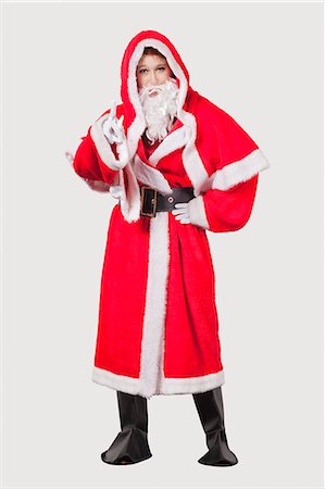 Portrait of young woman in Santa costume gesturing against gray background Stock Photo - Premium Royalty-Free, Code: 693-06435895