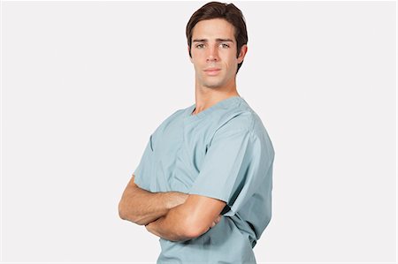 simsearch:693-06435879,k - Portrait de jeune confiant dans scrubs chirurgicales permanent sur fond gris Photographie de stock - Premium Libres de Droits, Code: 693-06435907