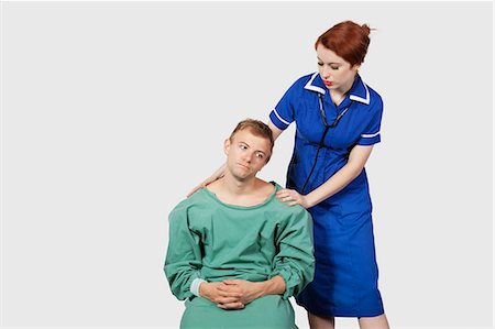 Female nurse consoling male patient against gray background Stock Photo - Premium Royalty-Free, Code: 693-06435919