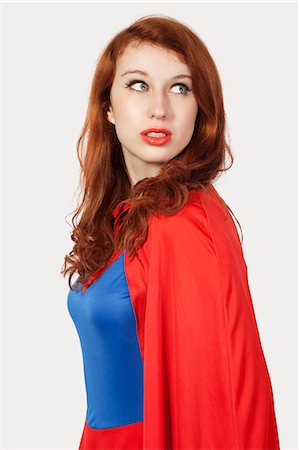 Young woman in superhero costume looking away against gray background Stock Photo - Premium Royalty-Free, Code: 693-06435933