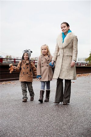 simsearch:693-06435996,k - Young woman with children in warm clothing walking together on street Fotografie stock - Premium Royalty-Free, Codice: 693-06435944