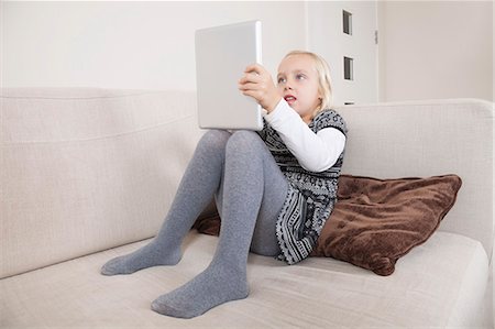 Jeune fille à l'aide de tablet PC sur canapé Photographie de stock - Premium Libres de Droits, Code: 693-06435965