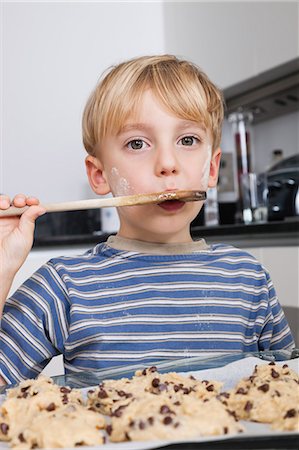 Portrait of young boy tasting spatula mix with cookie batter Stock Photo - Premium Royalty-Free, Code: 693-06435985