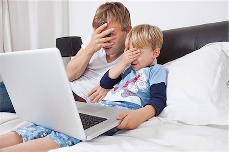 family scared - Père et fils, regarder un film effrayant sur ordinateur portable dans le lit Photographie de stock - Premium Libres de Droits, Code: 693-06435999