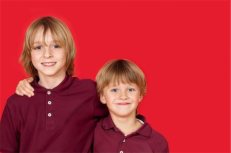 Portrait of two happy brothers against red background Stock Photo - Premium Royalty-Free, Code: 693-06436025