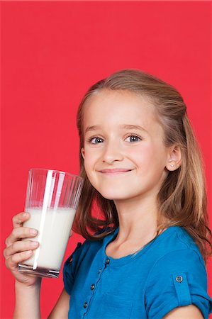 dietary supplement - Portrait of young girl holding glass of milk against red background Stock Photo - Premium Royalty-Free, Code: 693-06436045