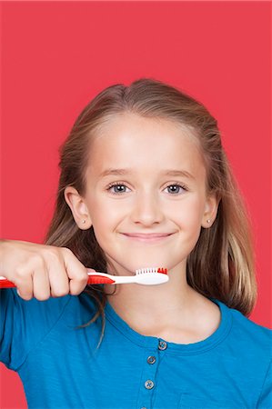 Portrait de jeune fille tenant la brosse à dents sur fond rouge Photographie de stock - Premium Libres de Droits, Code: 693-06436047