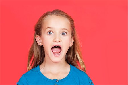 surprise people - Portrait of shocked young girl with mouth open against red background Stock Photo - Premium Royalty-Free, Code: 693-06436040