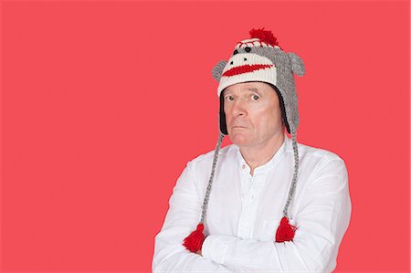 Portrait of confused senior man with arms crossed against red background Stock Photo - Premium Royalty-Free, Code: 693-06436051