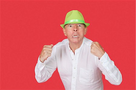 simsearch:693-07455845,k - Portrait of an angry senior man clenching fists against red background Fotografie stock - Premium Royalty-Free, Codice: 693-06436053