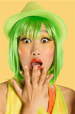 Portrait of shocked young woman with green hair against yellow background Stock Photo - Premium Royalty-Free, Code: 693-06436082