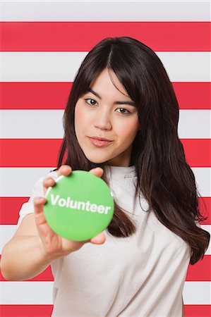 simsearch:693-06497571,k - Portrait of young woman holding out volunteer badge against American flag Stockbilder - Premium RF Lizenzfrei, Bildnummer: 693-06497568