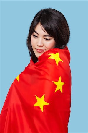digno - Patriotic young woman wrapped in Chinese flag over blue background Foto de stock - Sin royalties Premium, Código: 693-06497571