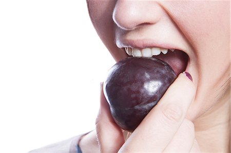 plum - Detail shot of young woman eating plum over white background Stock Photo - Premium Royalty-Free, Code: 693-06497605