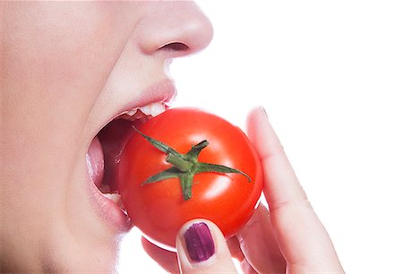 red fruit and white background - Detail shot of young woman eating tomato over white background Stock Photo - Premium Royalty-Free, Code: 693-06497607