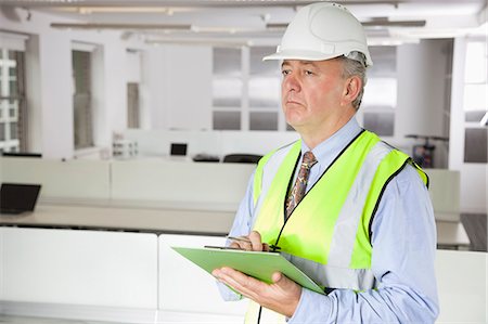 Middle-aged man in reflector vest and hard hat with clipboard at office Foto de stock - Sin royalties Premium, Código: 693-06497657