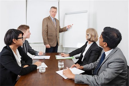 someone pointing at a group of people - Man using whiteboard in business meeting Stock Photo - Premium Royalty-Free, Code: 693-06497660