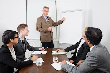 Middle-aged man using whiteboard in business meeting Stock Photo - Premium Royalty-Free, Code: 693-06497662