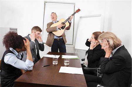Businessman playing guitar in business meeting Stock Photo - Premium Royalty-Free, Code: 693-06497674