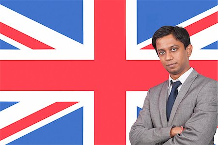 Portrait of young businessman with arms crossed over British flag Foto de stock - Sin royalties Premium, Código: 693-06497699