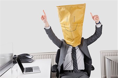 funny - Businessman cheering with smiley drawn on paper bag over face in office Stock Photo - Premium Royalty-Free, Code: 693-06497721