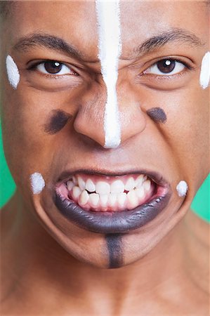 Detail shot of aggressive mixed race man with painted face clenching teeth Foto de stock - Sin royalties Premium, Código: 693-06497751