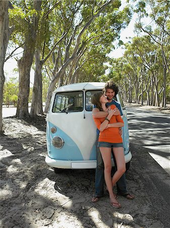 Young couple embracing leaning against front of camper van parked by road Stock Photo - Premium Royalty-Free, Code: 693-06667797