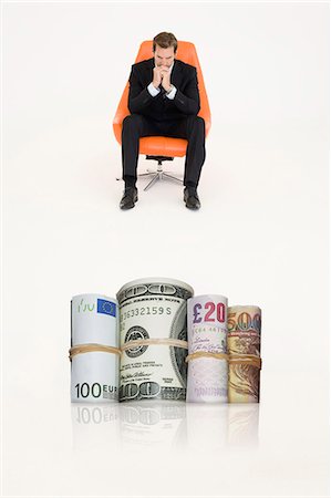 Money rolls with pensive businessman on chair representing financial problems Photographie de stock - Premium Libres de Droits, Code: 693-06667991