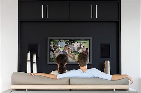 Back view of couple watching movie on television in living room Stock Photo - Premium Royalty-Free, Code: 693-06668028