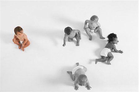 High angle view of baby girl looking at other babies crawling on floor Foto de stock - Sin royalties Premium, Código: 693-06668045