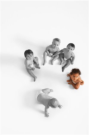 High angle view of baby girl looking up with other babies sitting on floor Foto de stock - Sin royalties Premium, Código: 693-06668046