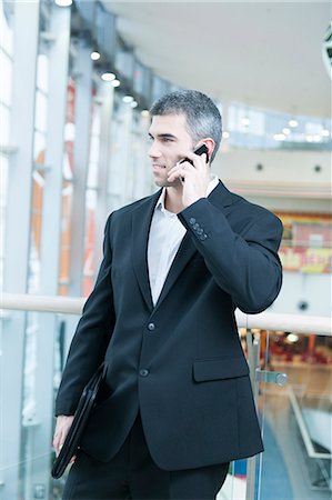 Businessman walking and talking on mobile phone Foto de stock - Sin royalties Premium, Código: 693-06967319