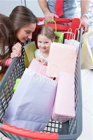 shopping mom kids - Close-up of young daughter in trolley being pushed by father and mother Stock Photo - Premium Royalty-Free, Code: 693-06967369