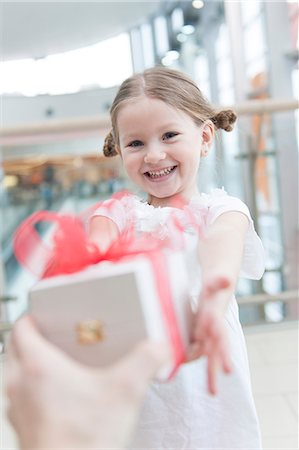 shopping center family - Young girl being giving a present Stock Photo - Premium Royalty-Free, Code: 693-06967378