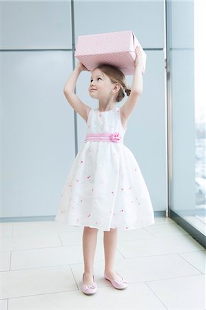 Young girl holding gift wrapped box on her head Stock Photo - Premium Royalty-Free, Code: 693-06967385