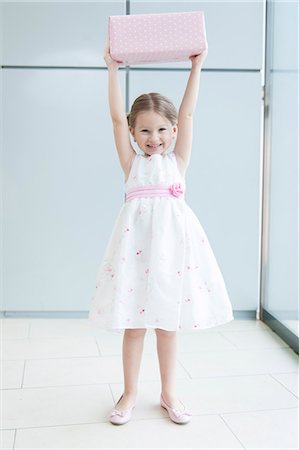 shopping girl image - Young girl holding gift wrapped box above her head Stock Photo - Premium Royalty-Free, Code: 693-06967386