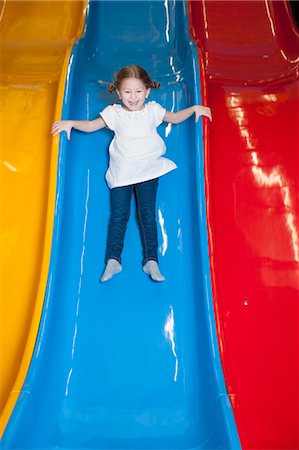 escorregar - Young girl slides down colorful slide Foto de stock - Royalty Free Premium, Número: 693-06967397