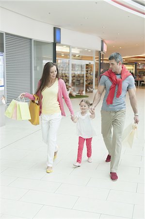 Young girl holding parents hands in shopping mall Photographie de stock - Premium Libres de Droits, Code: 693-06967406