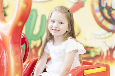 red white - Young girl sitting on childrens car ride Stock Photo - Premium Royalty-Free, Code: 693-06967403