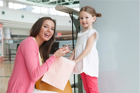 Mother giving daughter paper shopping bag Photographie de stock - Premium Libres de Droits, Code: 693-06967417