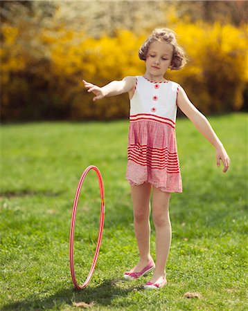 Young girl rolling hula hoop in park Foto de stock - Sin royalties Premium, Código: 693-06967425