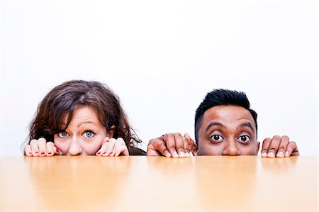 people peeking - Work colleagues peeking over edge of table Stock Photo - Premium Royalty-Free, Code: 693-06967505