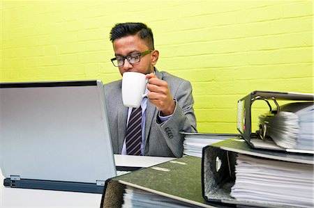 simsearch:693-03474486,k - Portrait of Indian Businessman holding mug and working on his laptop computer at his desk Foto de stock - Sin royalties Premium, Código: 693-06967514